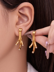 Gros plan de boucles d'oreilles dorées en forme de feuille avec oxydes de zirconium