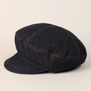Close-up of dark denim newsboy cap with contrast brown stitching and multi-panel design
