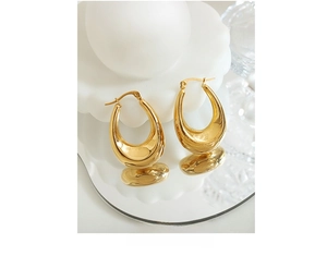 Detailed macro view of golden U-shaped chunky hoop earrings on a reflective pedestal
