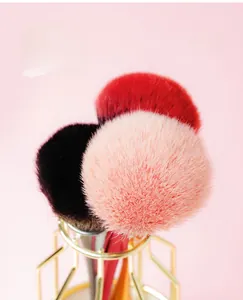 Detail showing soft fluffy pink nail dust brush heads with gold geometric metal stand