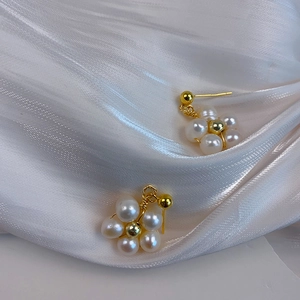 Macro detail of elegant flower-shaped pearl earrings on a soft white silk background