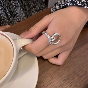 Minimalist silver knot ring for women worn by a hand holding a coffee cup in a cafe