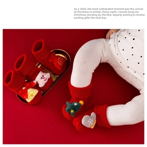 Detail of red baby Christmas socks featuring 3D Santa and tree charms with warm cuffs