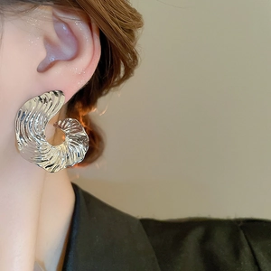 Close-up of silver irregular geometric earring with wave design on model's ear