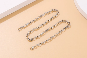Close-up of minimalist silver stainless steel chain link necklace on a neutral background