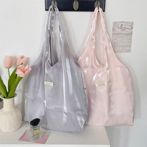 Detail of shimmering silver and pink tote bags hanging in a soft minimalist interior