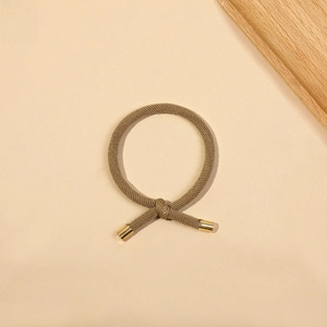 Detail view of a thick brown knotted hair tie with elegant gold metal tips