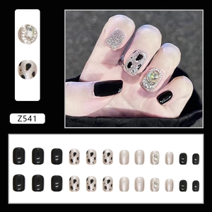 Black press-on nails with cow print, silver glitter, and large rhinestones in a 24pcs set