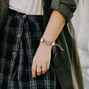 Handmade bohemian beaded bracelet featuring colorful woven cord and metal accents worn on wrist