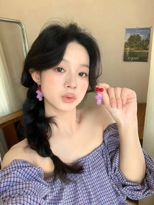 Détail de boucles d'oreilles pendantes en résine violette en forme de raisin sur un mannequin