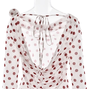 Detail of white dress with red polka dots featuring a draped back and lace-up straps