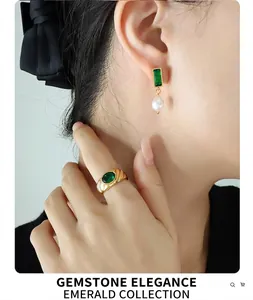 Detail of vintage gold ring with green zircon and pearl drop earrings on model