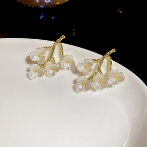 Detail of floral resin earrings with golden branch and frosted white flower petals