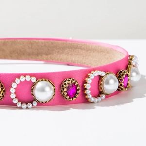 Detail of pink satin headband featuring faux pearls and magenta crystals in gold settings
