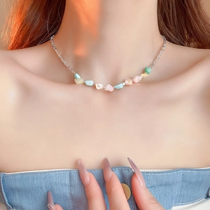 Close-up of a pastel natural stone necklace with silver chain on a female model