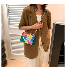 Detail of colorful geometric crossbody bag featuring golden chain strap on a model