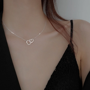 Intertwined double heart necklace in silver finish worn by a model on collarbone