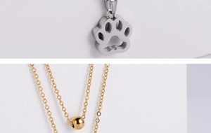 Macro detail of silver paw print pendant with gold bead chain in stainless steel