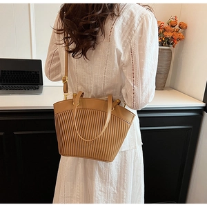 Detail of camel brown pleated leather tote bag with adjustable shoulder strap and handles
