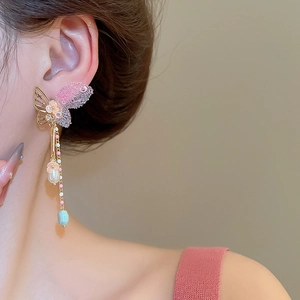 Detail of butterfly tassel earrings with crystals and pearls worn by a model