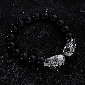 Close-up of black beaded men's bracelet featuring two detailed silver tiger head charms