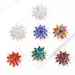 Macro view of crystal flower brooches in multiple colors on white geometric background