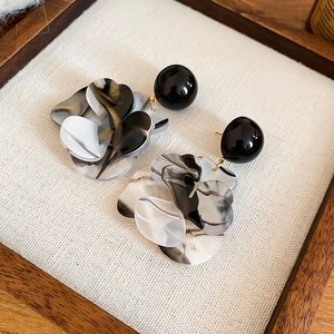 Détails de boucles d'oreilles fleur en résine marbrée avec clous noirs sur tissu