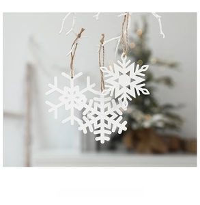 Close-up of white snowflake Christmas tree ornaments with rustic hemp rope hanging on branches