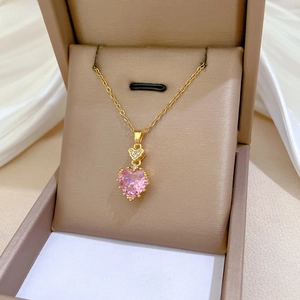 Close-up of heart-shaped pink zircon pendant on gold chain inside a luxury gift box