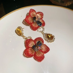 Macro di orecchini a fiore ricamati rossi con gemme a goccia gialle e dettagli dorati