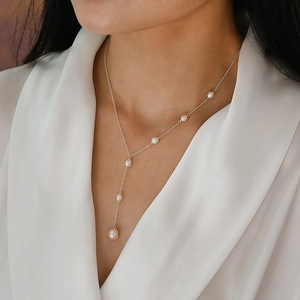 Detail of elegant Y-shaped silver necklace with freshwater pearls on a female model