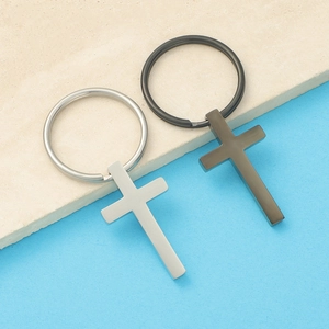 Polished stainless steel cross keychains in silver and gun black on textured background
