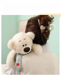 Primer plano de un oso de peluche blanco con bufanda de punto gris y un corazón rojo bordado
