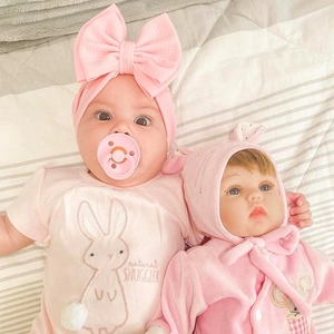 Detailed view of pink double bow headband with matching baby romper and pacifier