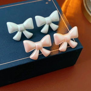 Macro shot of white and pink pearlescent bow earrings on a blue jewelry box display