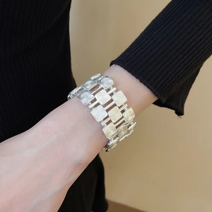 Close-up of silver metal stretch bracelet with square textured spiral pattern links