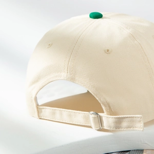 Dettaglio della fibbia in metallo e della trama in twill beige di un cappellino