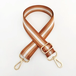 Detail of adjustable nylon strap with brown white stripes and golden metal buckles