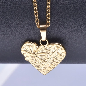 Détail macro du pendentif cœur plaqué or 18 carats avec texture florale embossée