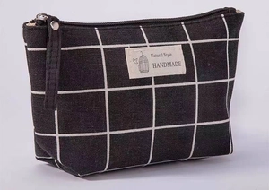 Close-up of checkered canvas makeup bag featuring a handmade label and metal zipper detail