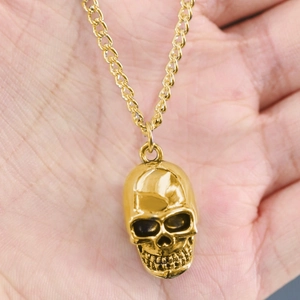 Detailed close-up of a hip hop style golden skull pendant necklace for men in hand