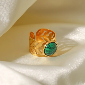 Detailed macro view of 18K gold ring featuring a green stone and filigree leaf design
