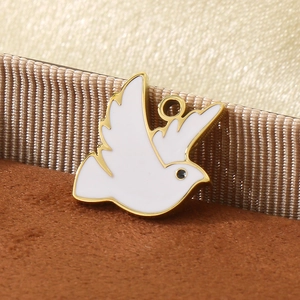 Detailed close-up of a white enamel peace dove charm with golden plating and small loop