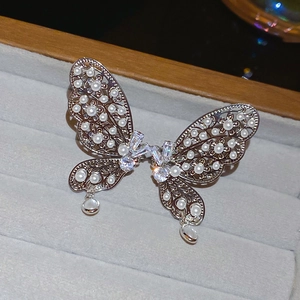 Vue détaillée de la boucle d'oreille papillon avec perles et zircons sur plateau gris