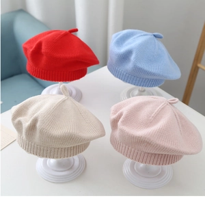 Multi-color baby knit berets in red, light blue, beige, and pink on white display stands