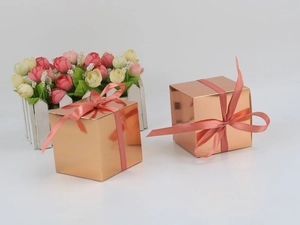 Detail of square rose gold gift boxes featuring glossy finish and pink ribbon bows