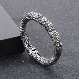 Macro detail of retro silver dragon scale engraving on a wide textured cuff bracelet