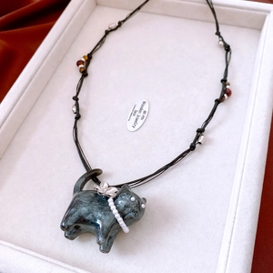 Detail shot of a resin cat pendant necklace with pearl and flower accents.
