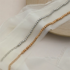 Detailansicht eleganter Perlenketten in Gold und Silber auf feinem weißem Tüllgewebe
