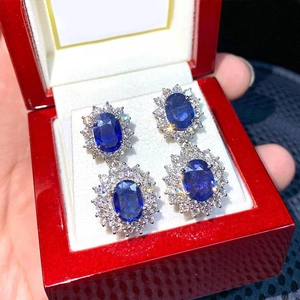 Dettaglio di orecchini con zaffiro blu e halo di diamanti in una scatola regalo rossa